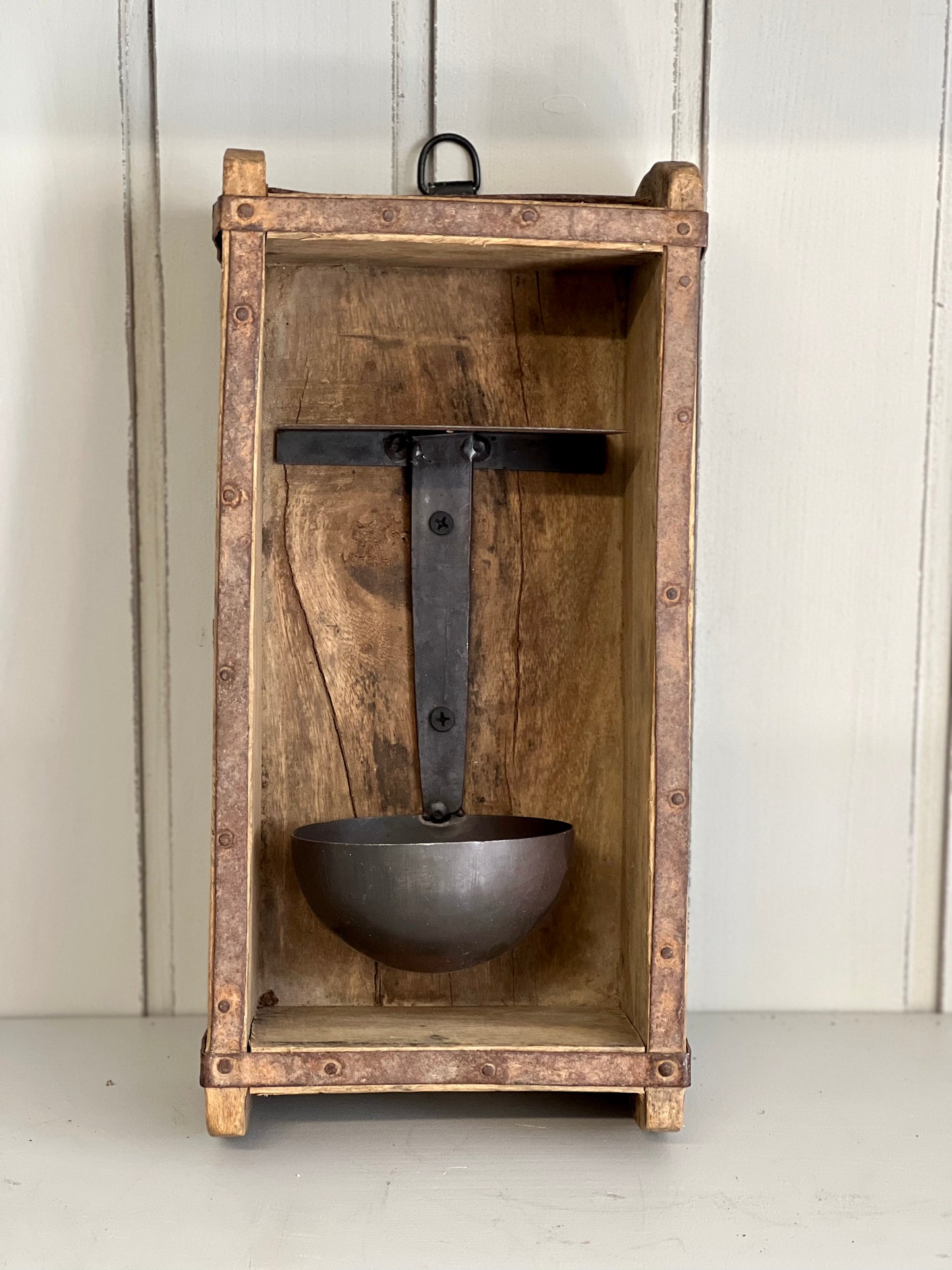 Rustieke houten wanddecoratie met een metalen lepel en een ophanghaak.
